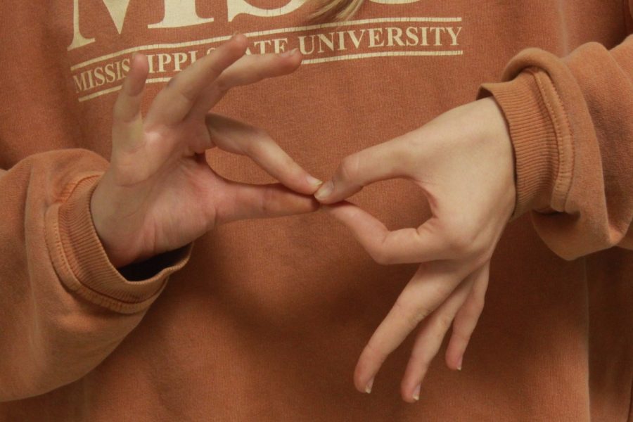 A student demonstrating the ASL sign for “interpreter”.