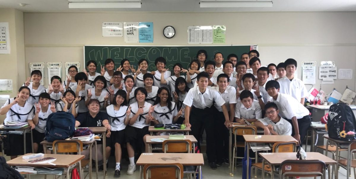 Kaitlin Mottley (11) smiles for a picture with students from Itoman Prefectural