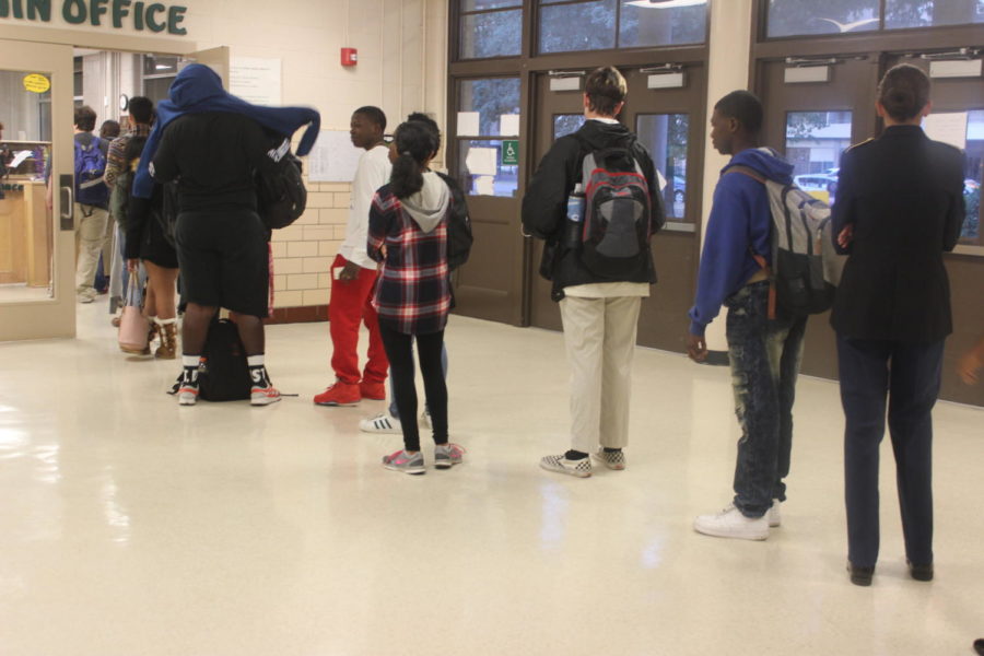 Students line up to collect a tardy slip from the office before school 

