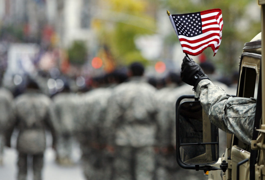A serviceman waves the American flag during a parade.