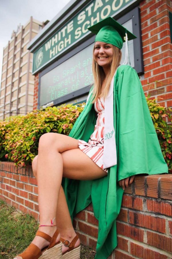 Bayley+Jones+%2812%29%2C+dressed+in+her+green+cap+and+gown%2C+poses+in+front+of+White+Station+High+School.+The+Spartan+Class+of+2020+received+their+caps+and+gowns+on+their+designated+locker+clean+out+day.+
