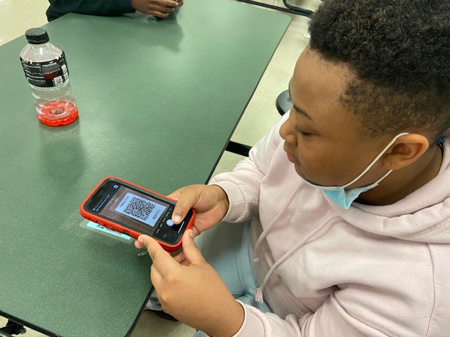 Aniyah Thompson hovers her phone over a QR code in the cafeteria that links to mandatory contact tracing. Lunchtime poses an obvious risk for in-person students, prompting heavy guidelines and monitoring to preserve safety. 


