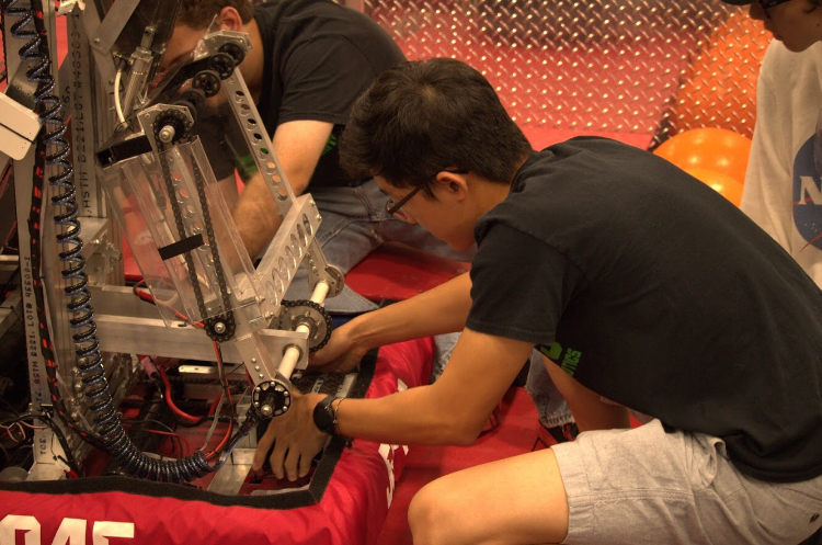 Completing a last minute touch-up before a match, Andrew Chen (12) changes the battery on team 5045’s robot. The match was part of an off-season competition known as the First Robotics Challenge in Arkansas. 
