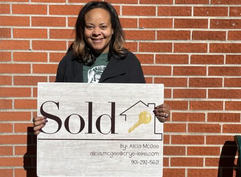 Alicia McGee holds up a personalized sign she gives her clients when they purchase their homes. McGee is a certified realtor in addition to an environmental science teacher.