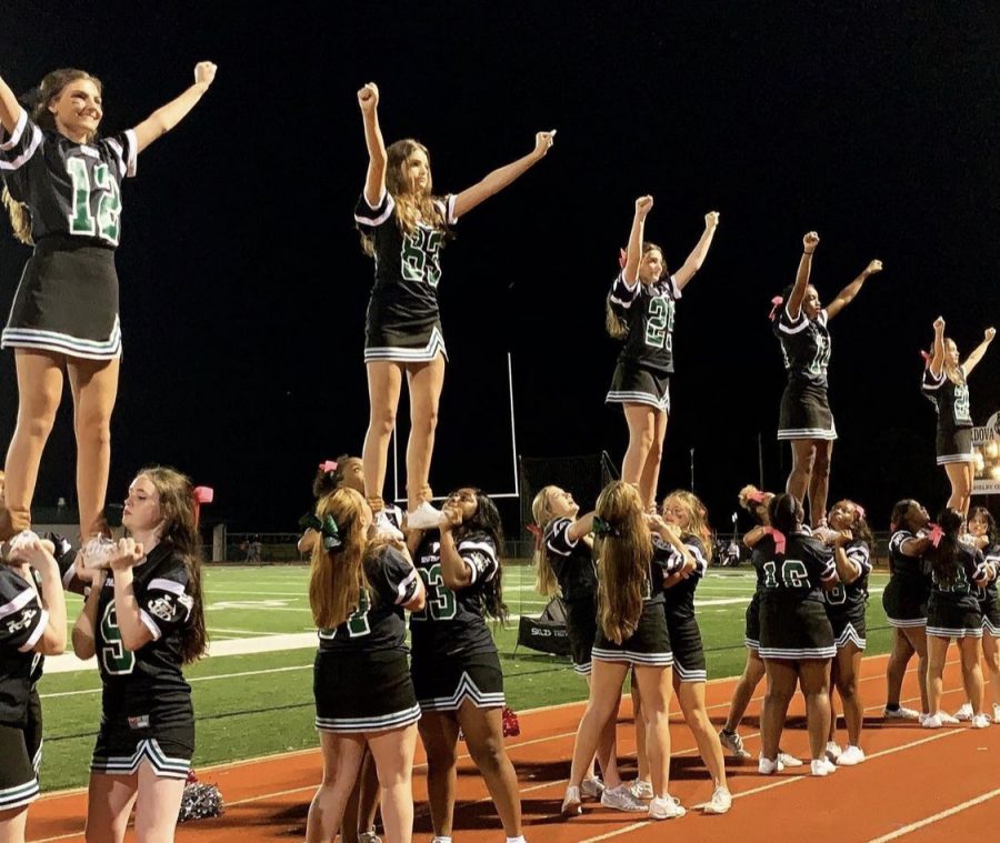 Cheerleaders stunt during a football game. Oftentimes, students watch dances and chants on the sidelines, but are unaware of the difficult stunts that are a large part of the separate competitions cheerleaders partake in.