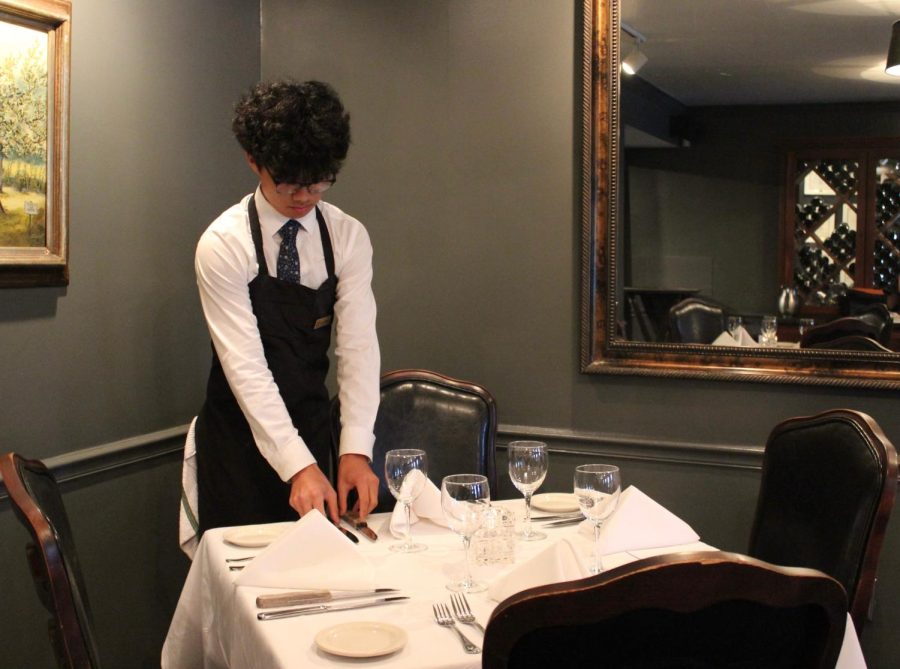 Matthew Kim (12) intricately sets up a table before diners arrive. Kim, like many other White Station students, works as a server assistant at fine dining steakhouse Folk’s Folly.
