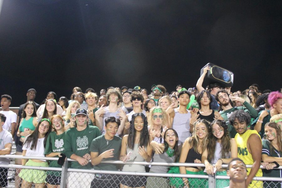 The student section turns up in support of the football team. Everyone is dressed in the school colors of green and gray.

