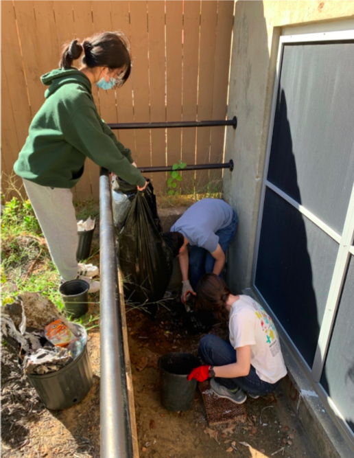 Ellen Tan (10), Anthony Nguyen (10) and other student volunteers work diligently with Spruce Up Sparta to help pick up trash wedged in a crevice within the courtyard. 
