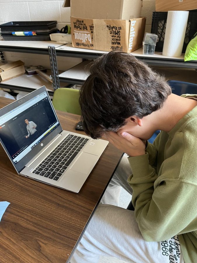 Luke Mallory (12) listens to a video by Ben Shapiro addressing the latest loan forgiveness policies. Watching a video entirely before beginning any writing is part of Mallory’s process in creating content for his blog.	