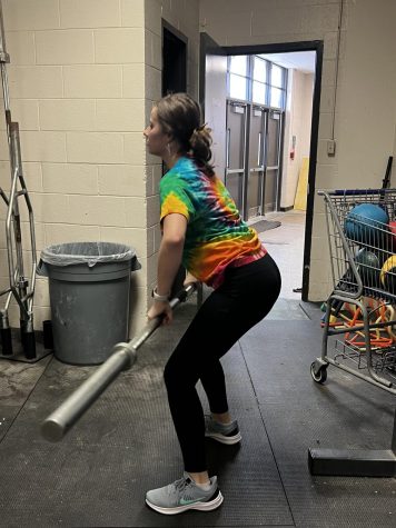Holly Cole (11) performs a hang-clean with the barbell. The softball team trains in the East Gym to increase their strength and athleticism.