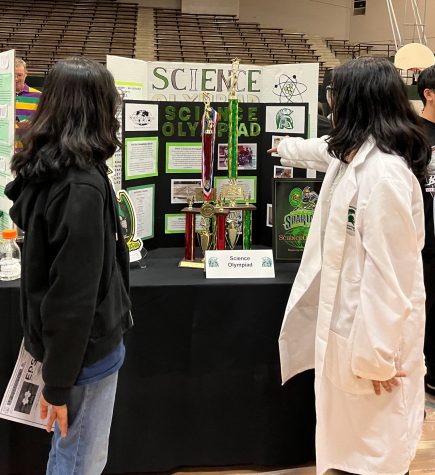Presenters and students stand around a poster board promoting the Science Olympiad team at EPSO night. EPSO night was hosted to exhibit the several classes, organizations and sports that White Station offers.