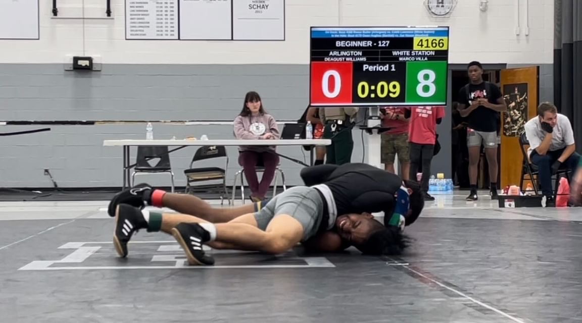 Marco Villa (11) pins his opponent in a preseason tournament. To win a match, wrestlers must score points by forcing their opponents to their hands or escaping holds, or pinning them to their backs to automatically end the match.