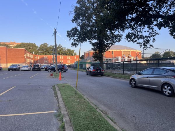 The East parking lot has been transformed into a parent drop-off zone. Parents are guided by Mr. Bowen and Sergeant Boyd through the two outer lanes of the lot, most stopping near the East gym to let their students out. 
