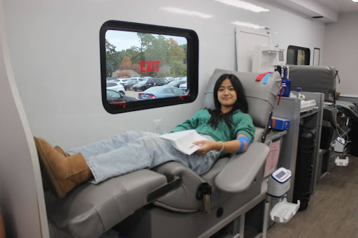 Catherine Cheng (11) reads the post-donation reminders following her blood donation. Once students completed their donation, Vitalant staff provided them with a trifold with info about how to sustain their health following their donation. 