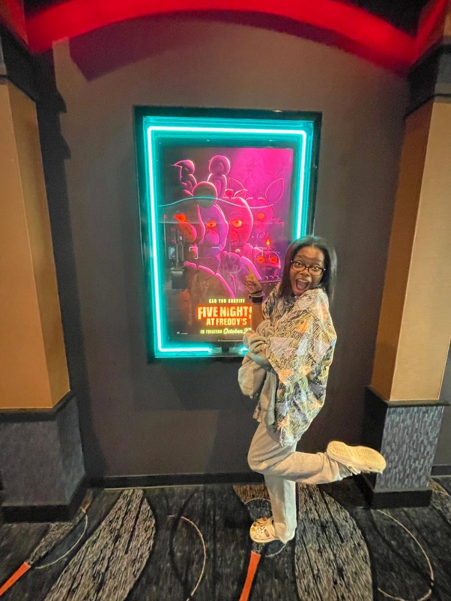  Larsen Thompson (9) poses in front of one of the official “Five Nights at Freddy’s” (FNaF) movie posters. The movie was released on Oct. 27, starring Josh Hutcherson. 
