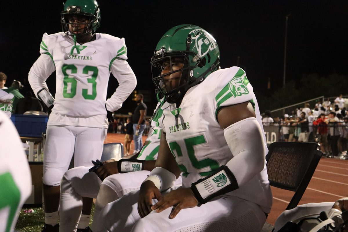 Chancellor Gray (12), number 65, waits on the sidelines for the second half of the game to begin. Although he does not want to play football in college, he has risen to a position of responsibility in the team because of his leadership and skill.