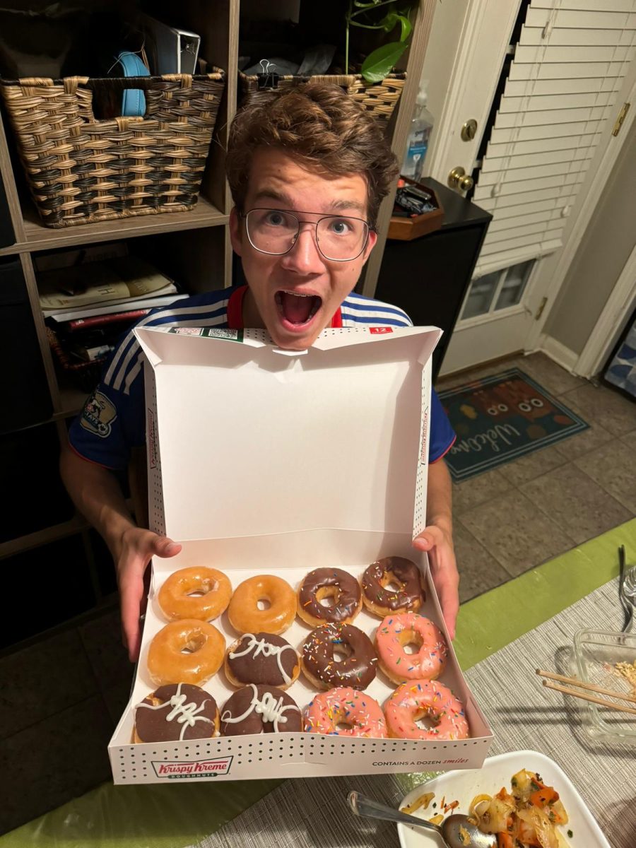 Luian Stiegler (11) poses with a box of Krispy Kreme donuts, his first taste of American food. Stiegler, originally from Stuttgart, Germany, misses his hometown's food — particularly Maultaschen gebraten, a traditional type of ravioli from his region.