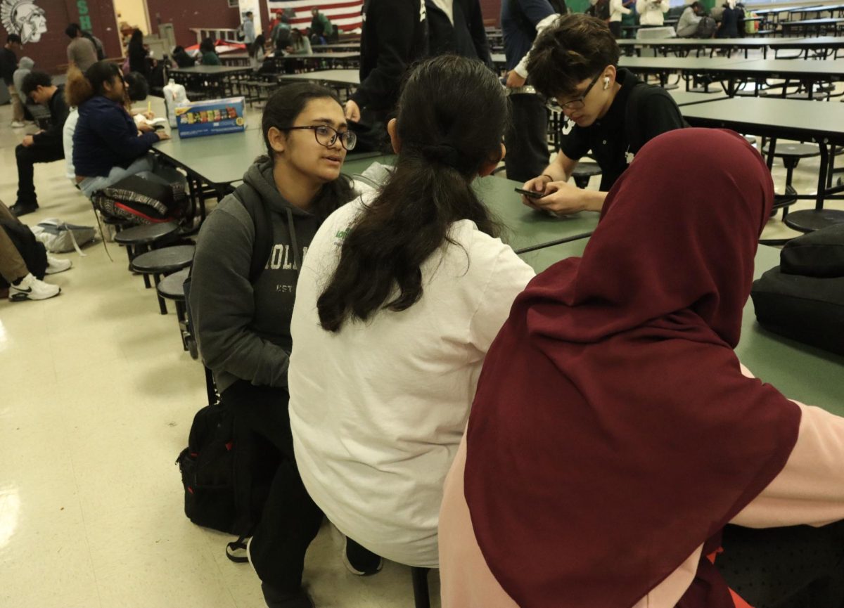 Afifah Alma (11) speaks with Ashmita Karmaker (9) in the cafeteria, before the first bell. Many of the Bangladeshi students at White Station have been close friends for years and often sit with each other at school and visit outside of school. 
