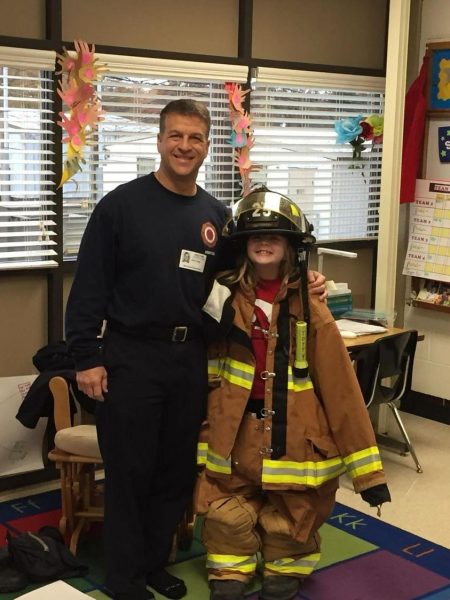 Young Allison Totty (12) poses with her father, John Totty, in some of his equipment. She grew up with stories of her dad and his work as a firefighter. 