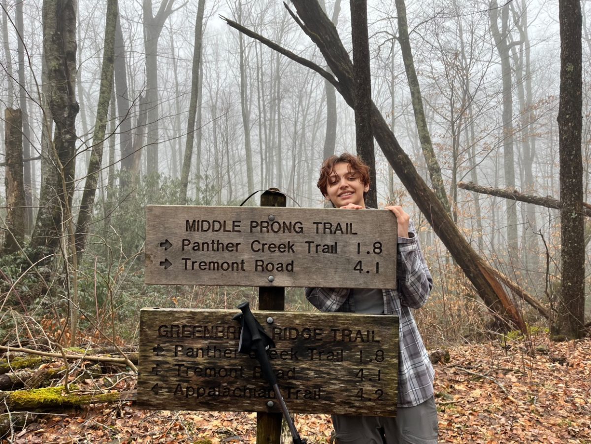 Aaron Marin poses for the camera as she stands in-front of a sign mentioning what trail she is on. Aaron walked along the Middle Prong Trail because her dad suggested it and brought her along.