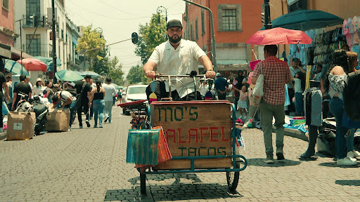 Stranded and determined, Mo Najjar dives into the street food hustle with his falafel taco cart. Every taco was sold with resilience and determination to find his way back home. 