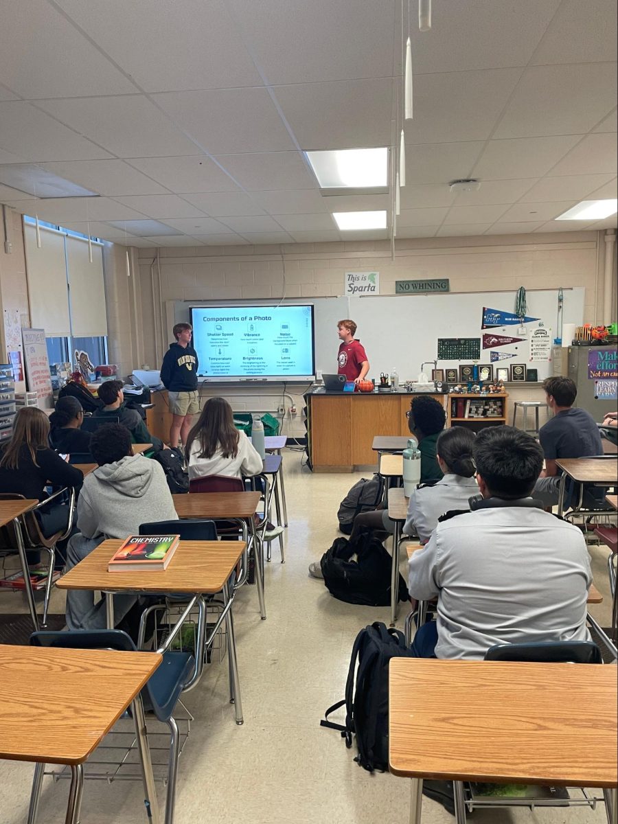 Charlie Russell (left) and Stewart Westbrook (right) teach photography basics to Spartan Sports Media Club members. Club members are tasked with going to one sports event every two weeks to take pictures.