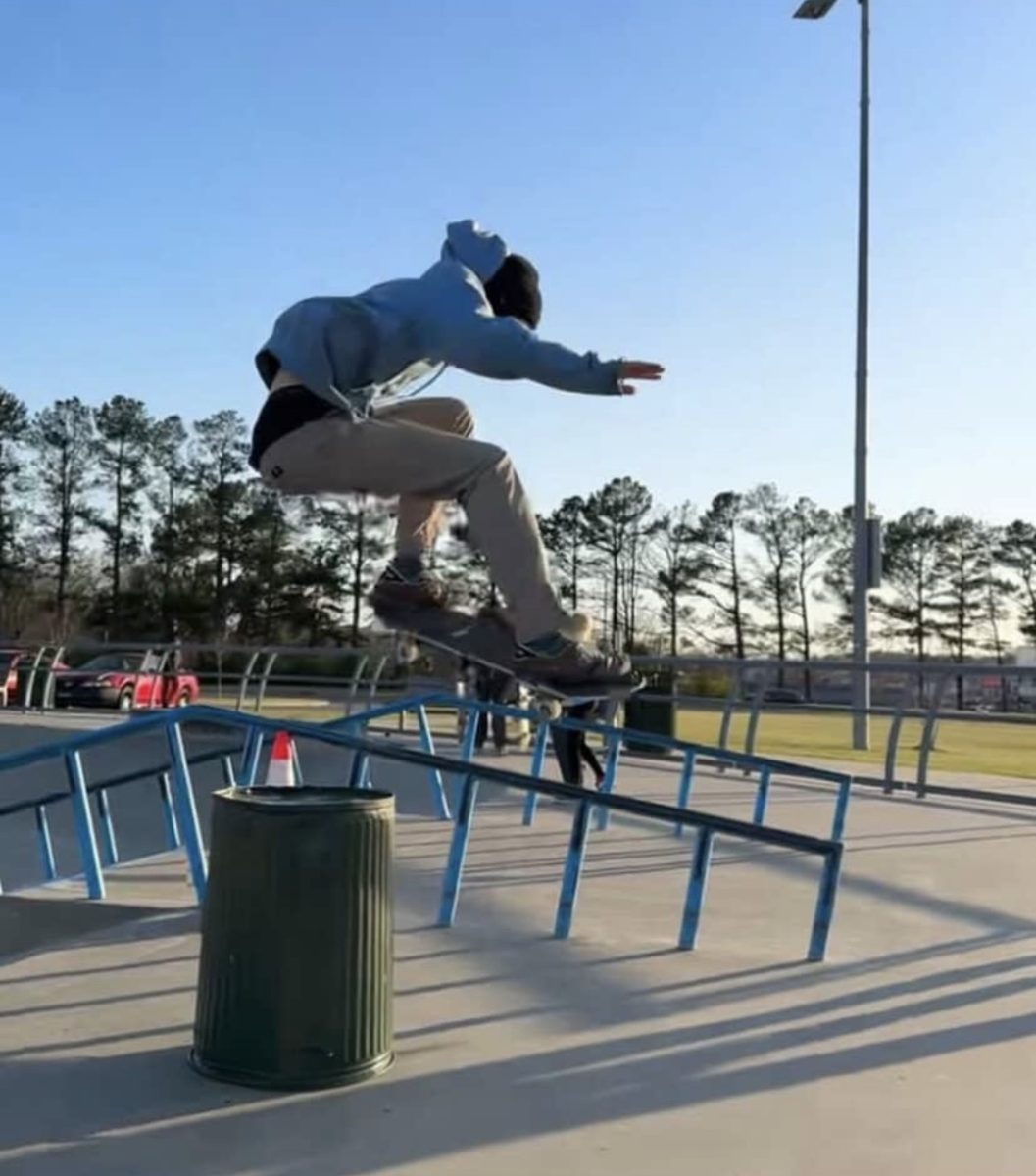 Orion Alwill (10) performs an Ollie over an obstacle at a skate park. The Ollie is a classic skateboarding trick where the skateboarder jumps into the air on their skateboard.