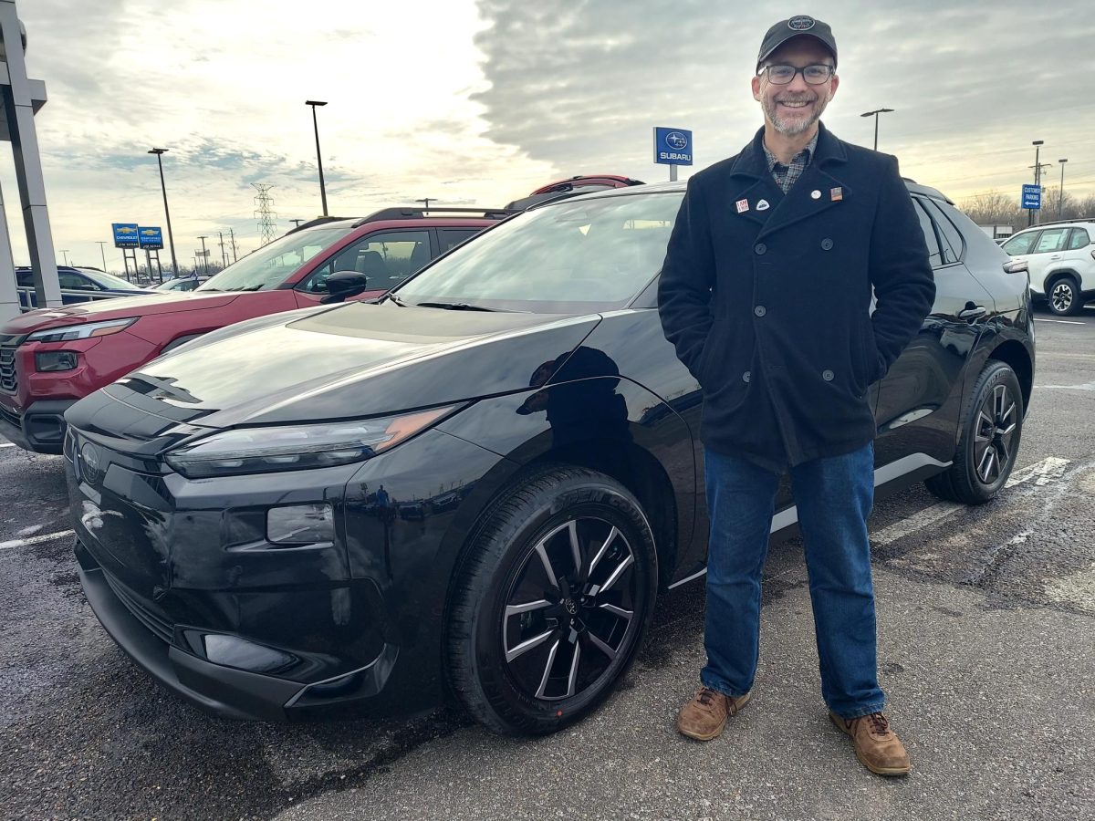 Kyle Tingley stands with his new electric vehicle (EV). The vehicle was long-term loaned to him by the dealership because Tingley had concerns about its longevity.