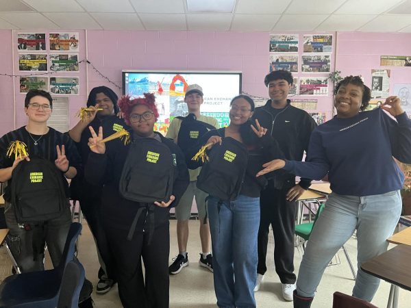 (From left to right) Theo Scarlett (12), Anthony Bowen (12), Allison Law (12), Christopher Kirkland (12), NaCoria Love (12), Javien Buggs (12) and Donna Settle pose at their American Exchange Project party. Settle hosted this party to announce which cities across the U.S. students would be traveling to.
